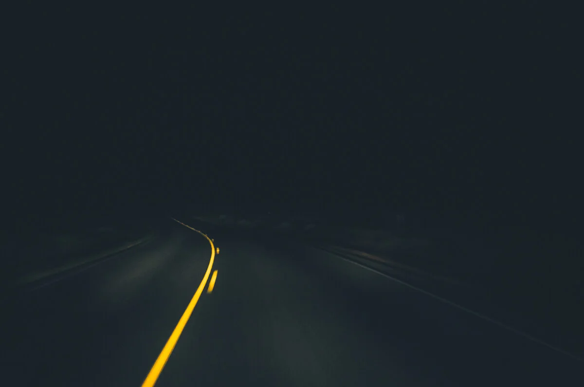 A moving shot of a curve in the road at night.