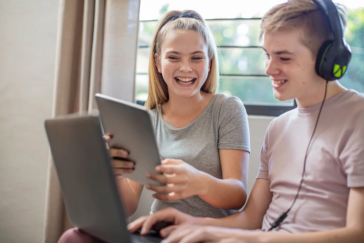 Happy boy and teenage girl with tablet, laptop and headphones