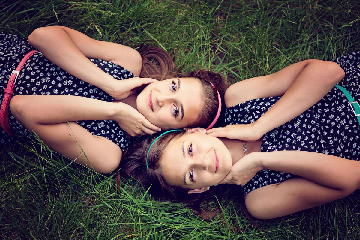 Twin sisters lying in the grass