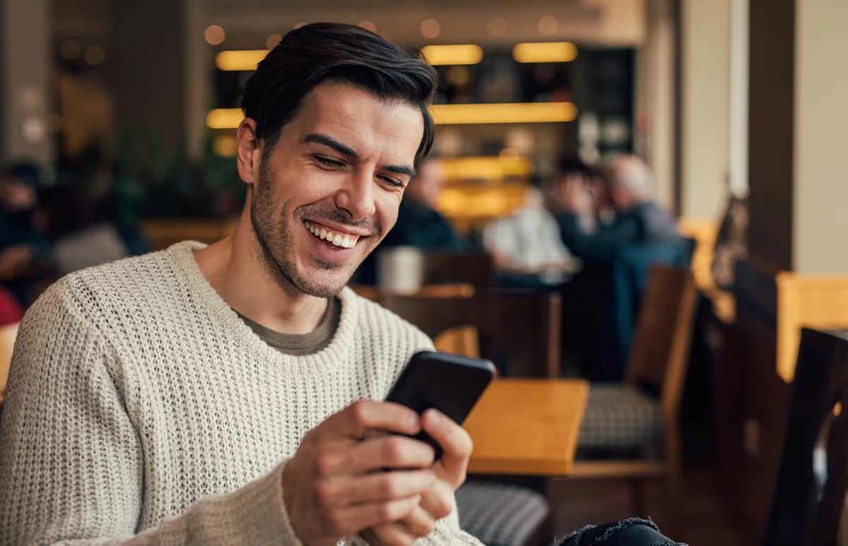 Young man using a smart phone at the cafe