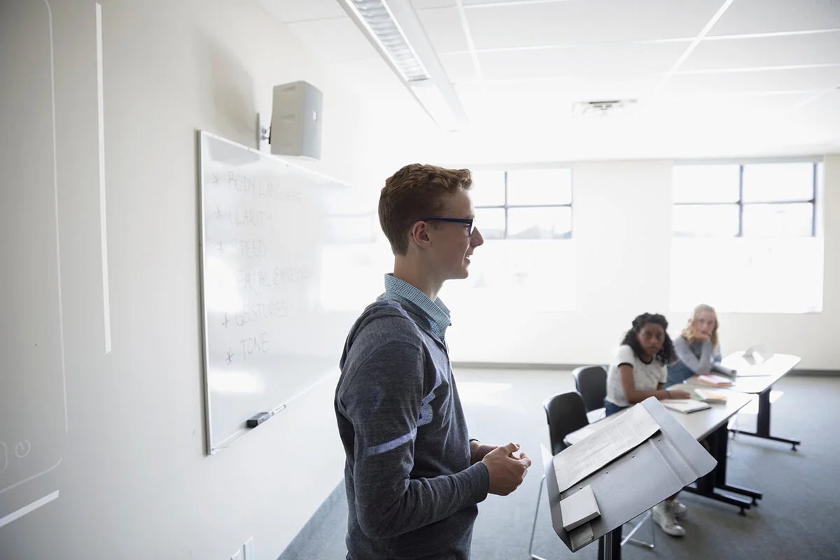 teen boy talking in front of peers in classroom