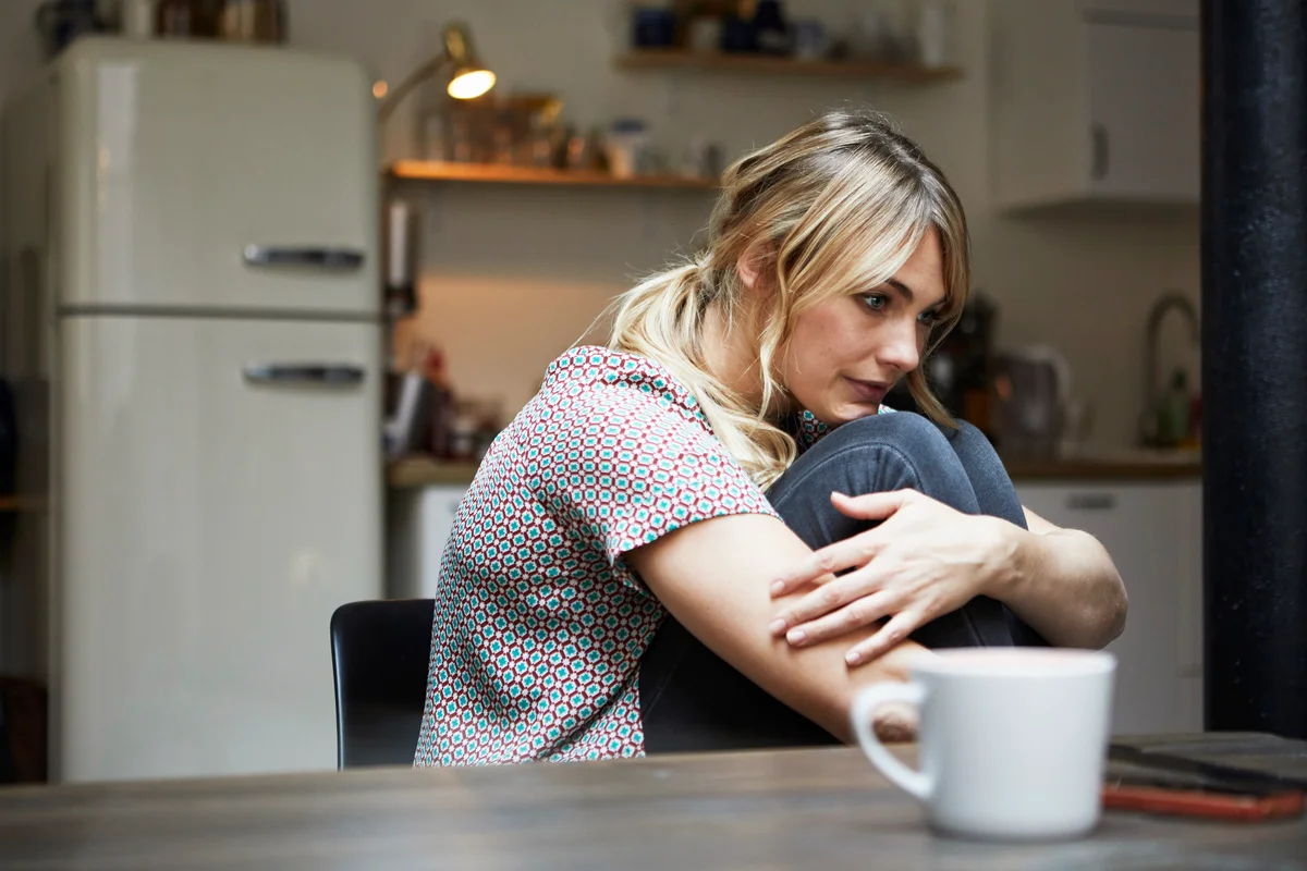 Pensive woman sitting at table in the kitchen