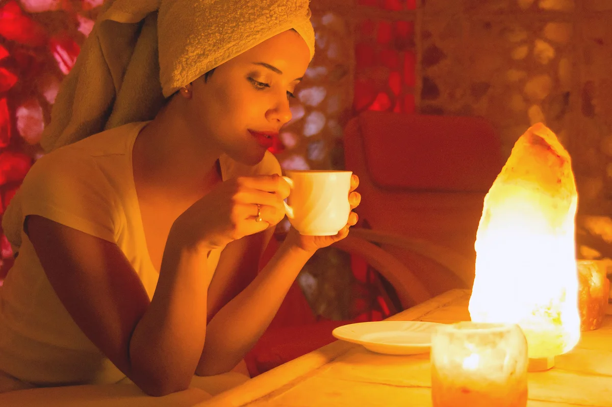 Woman drinking tea in front of salt lamp