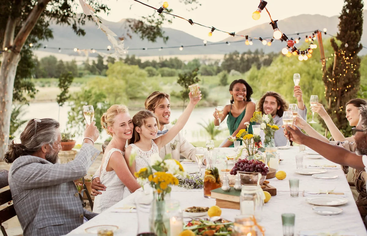 Young couple and guests toasting with champagne during wedding reception in domestic garden