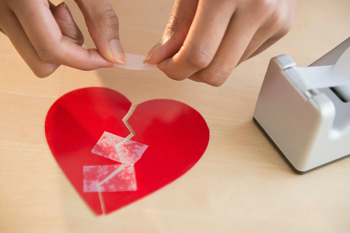 woman taking broken paper heart