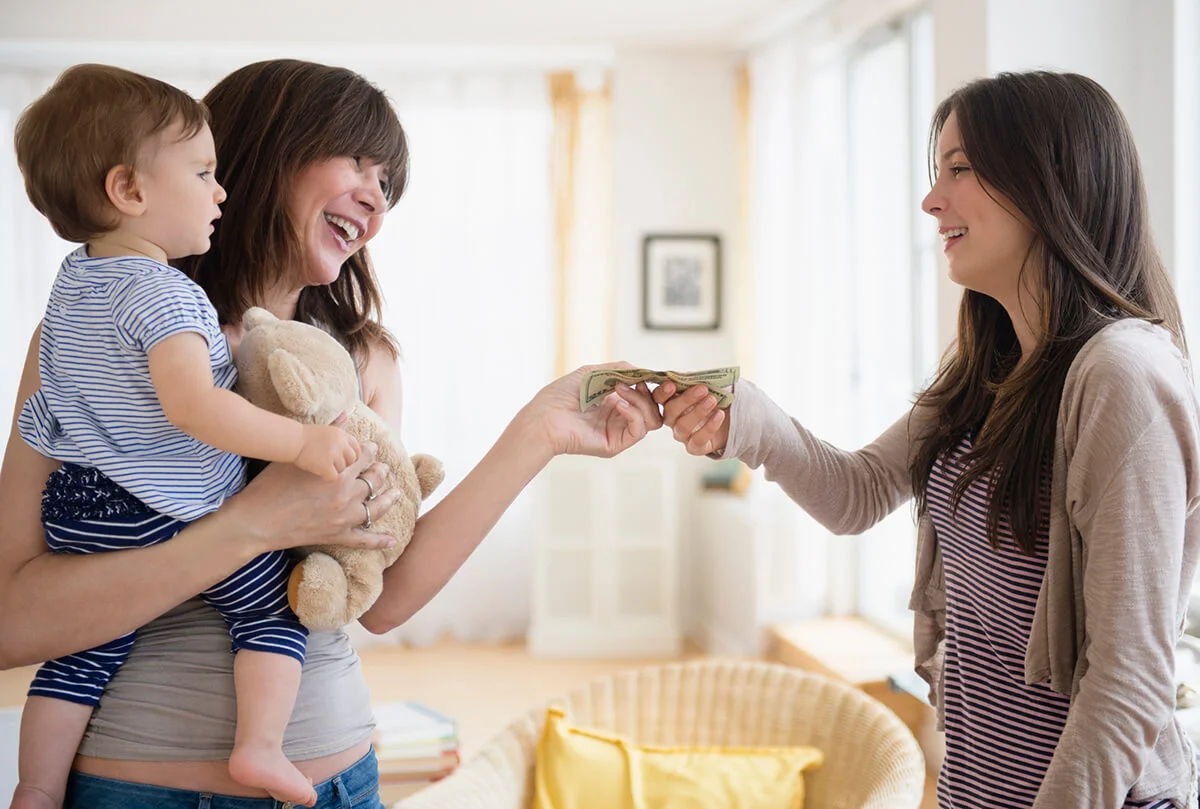 Woman paying teenage nanny for taking care of her son