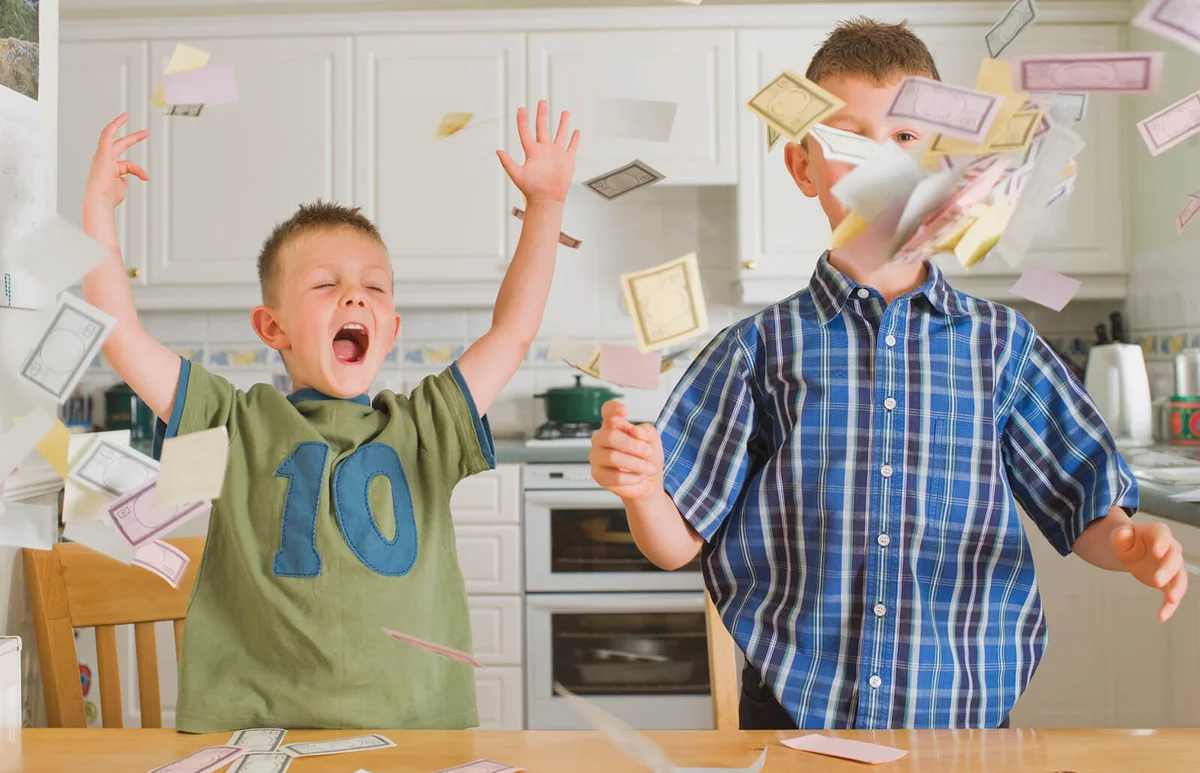 brothers playing with toy money in kitchen