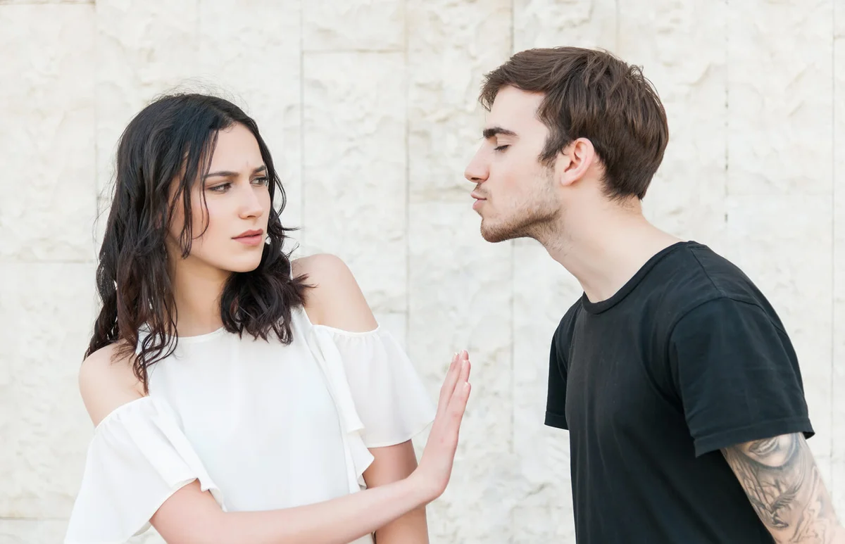 Young man trying to kiss a young woman
