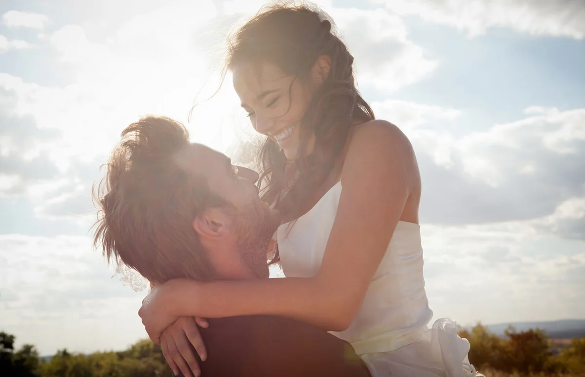 Newlywed groom holding bride outdoors