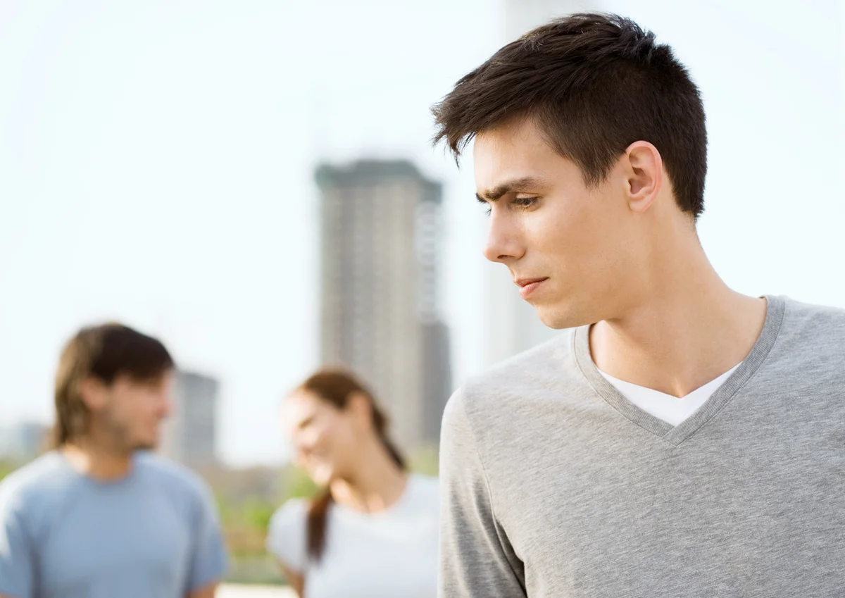 Young man looking to the side, young couple in background
