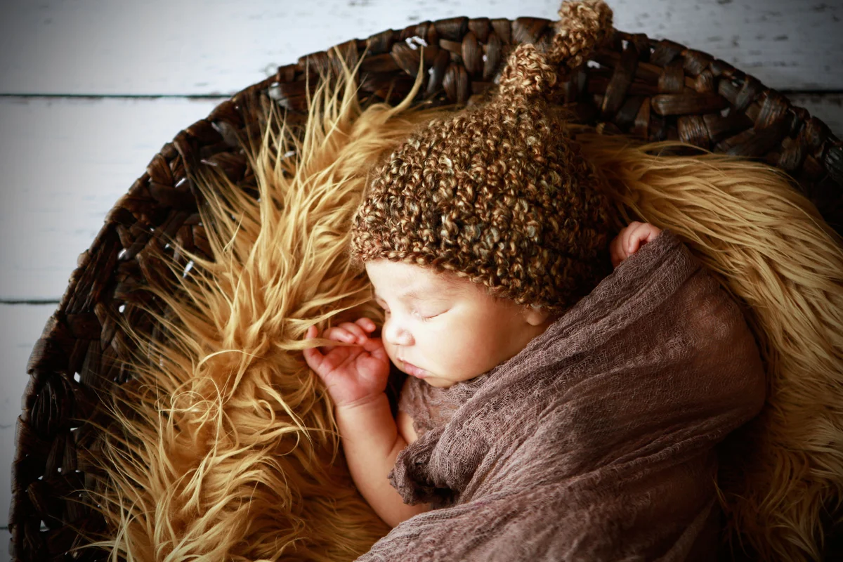 Newborn sleeping in fur lined basket