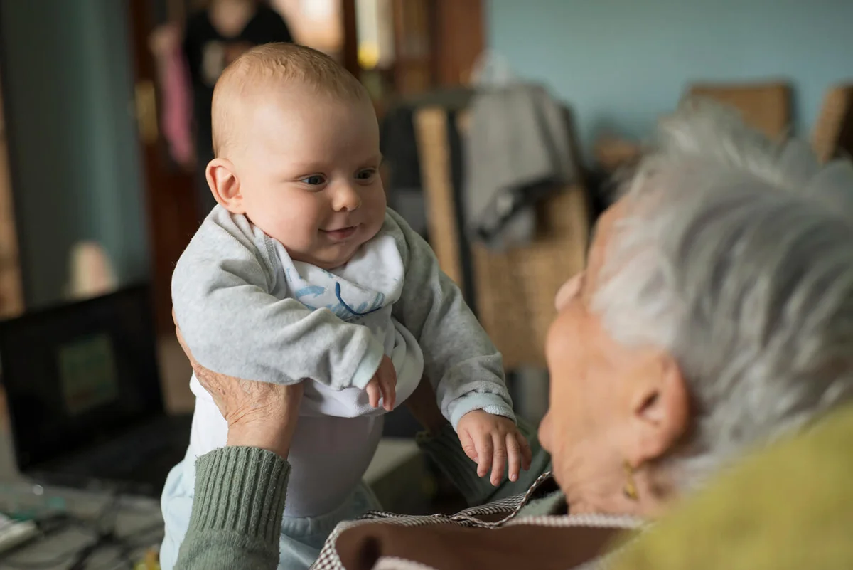 Baby boy smiling to an elderly woman at home
