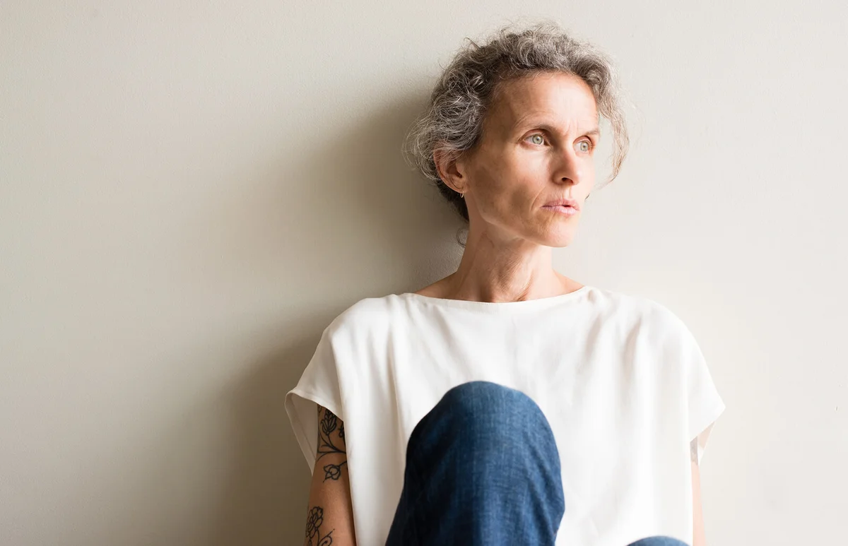 Woman Sitting By Wall