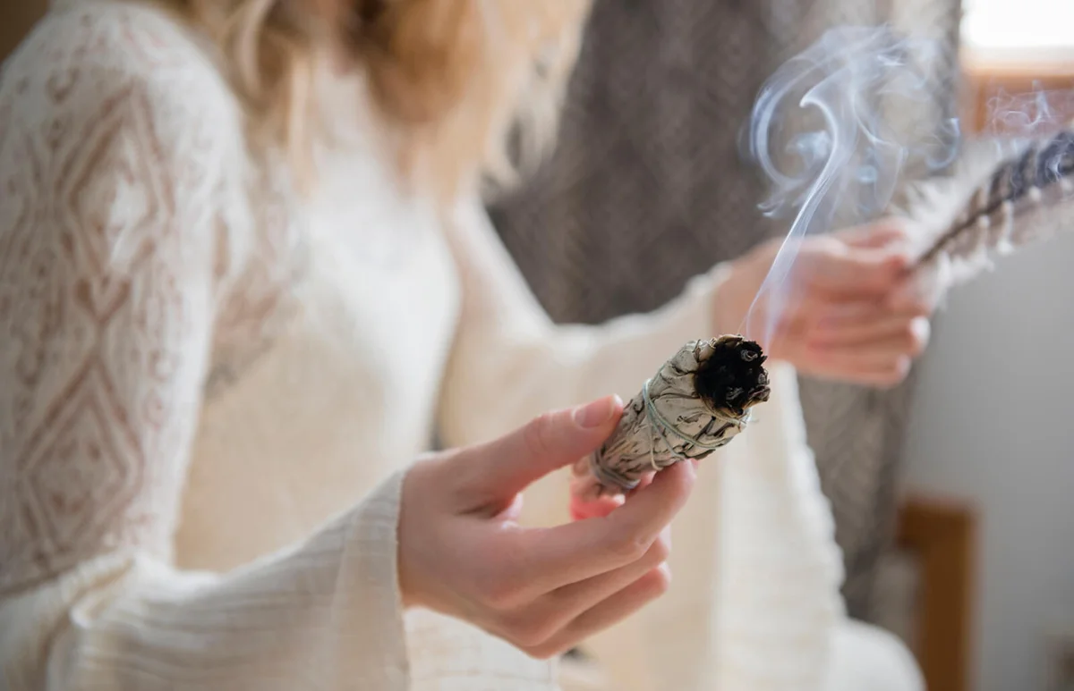 woman holding a feather and ritual incense