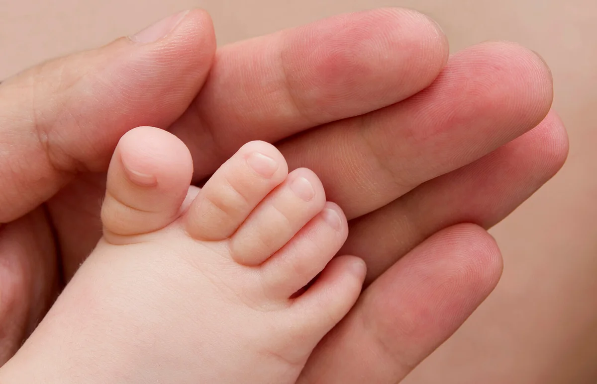 Baby foot held in parent's hand