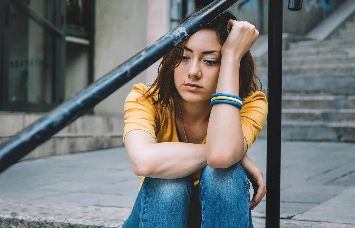 Sad teenager sitting on stairs in the city