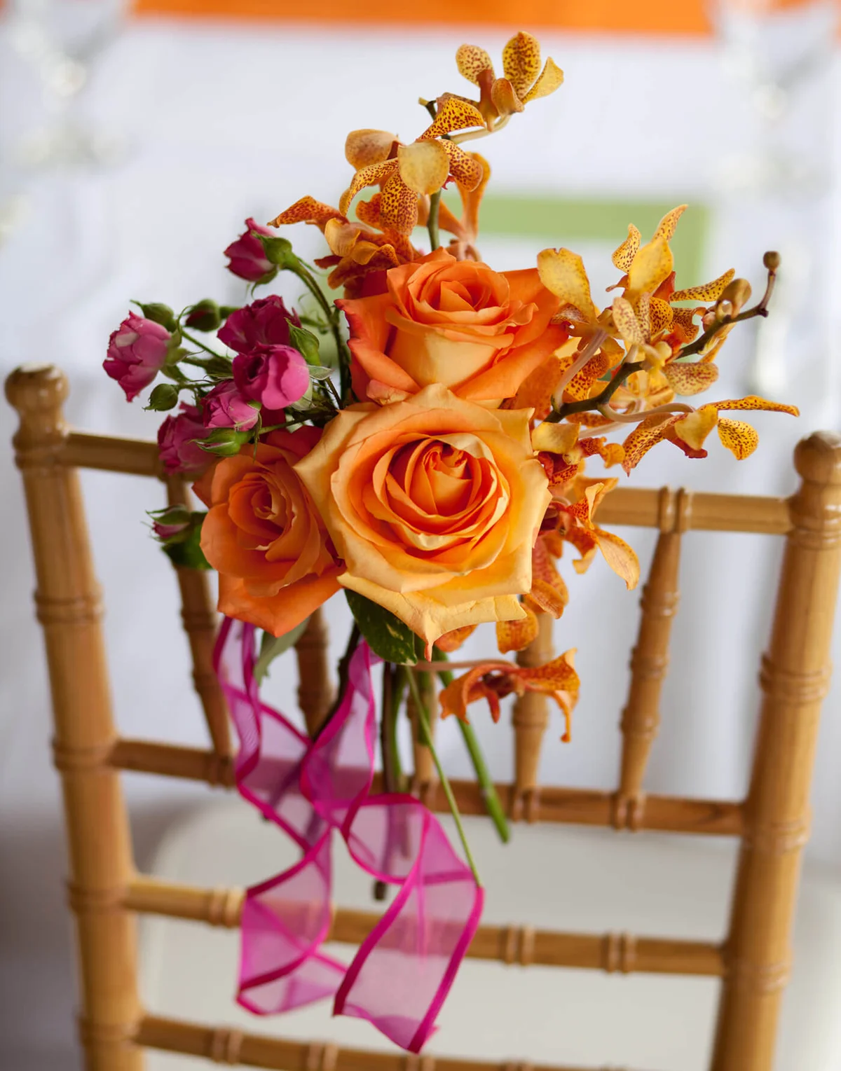 chair at a wedding decorated with a bunch of orange, yellow and pink flowers