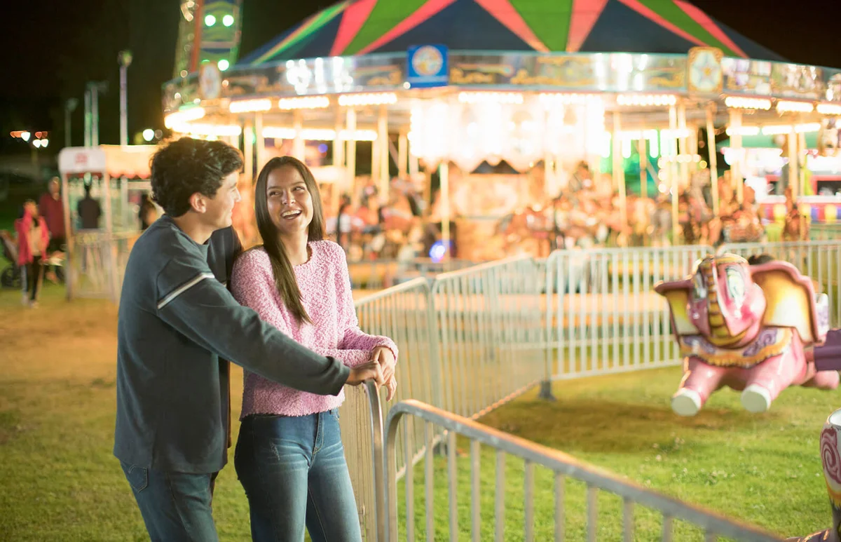 Young teenage couple at the fair at night