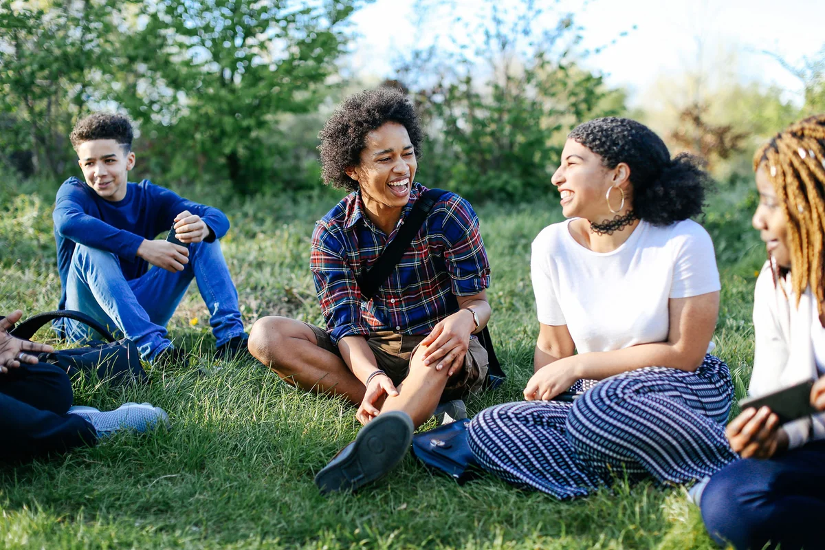 Group of teens sitting on grass laughing