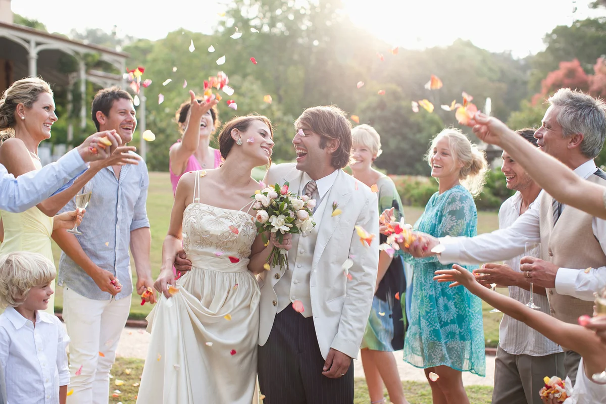 Guests throwing rose petals on bridal couple