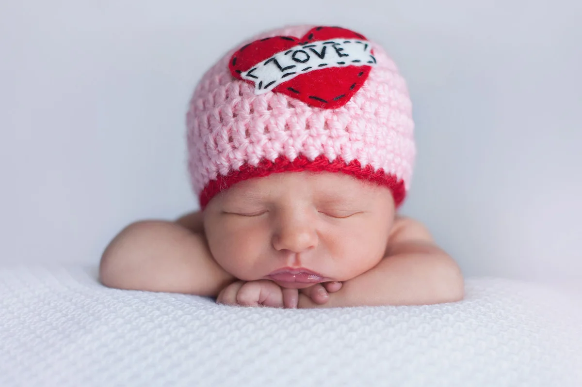 newborn baby wearing love hat