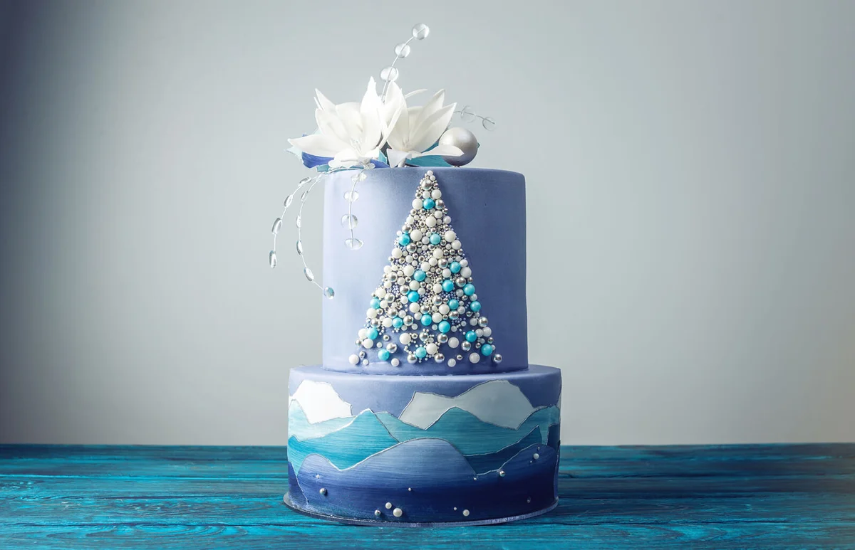 blue cake with the image of a Christmas tree and white flowers on top