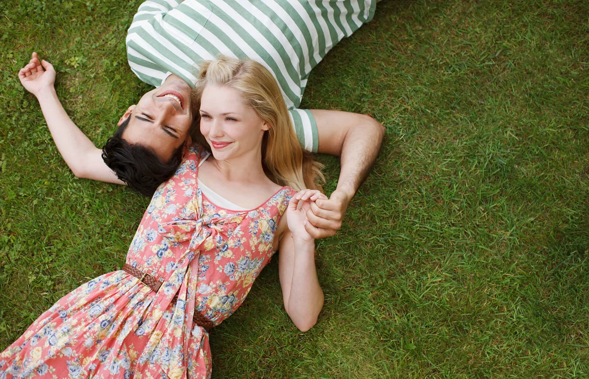 Young couple laying in grass and holding hands