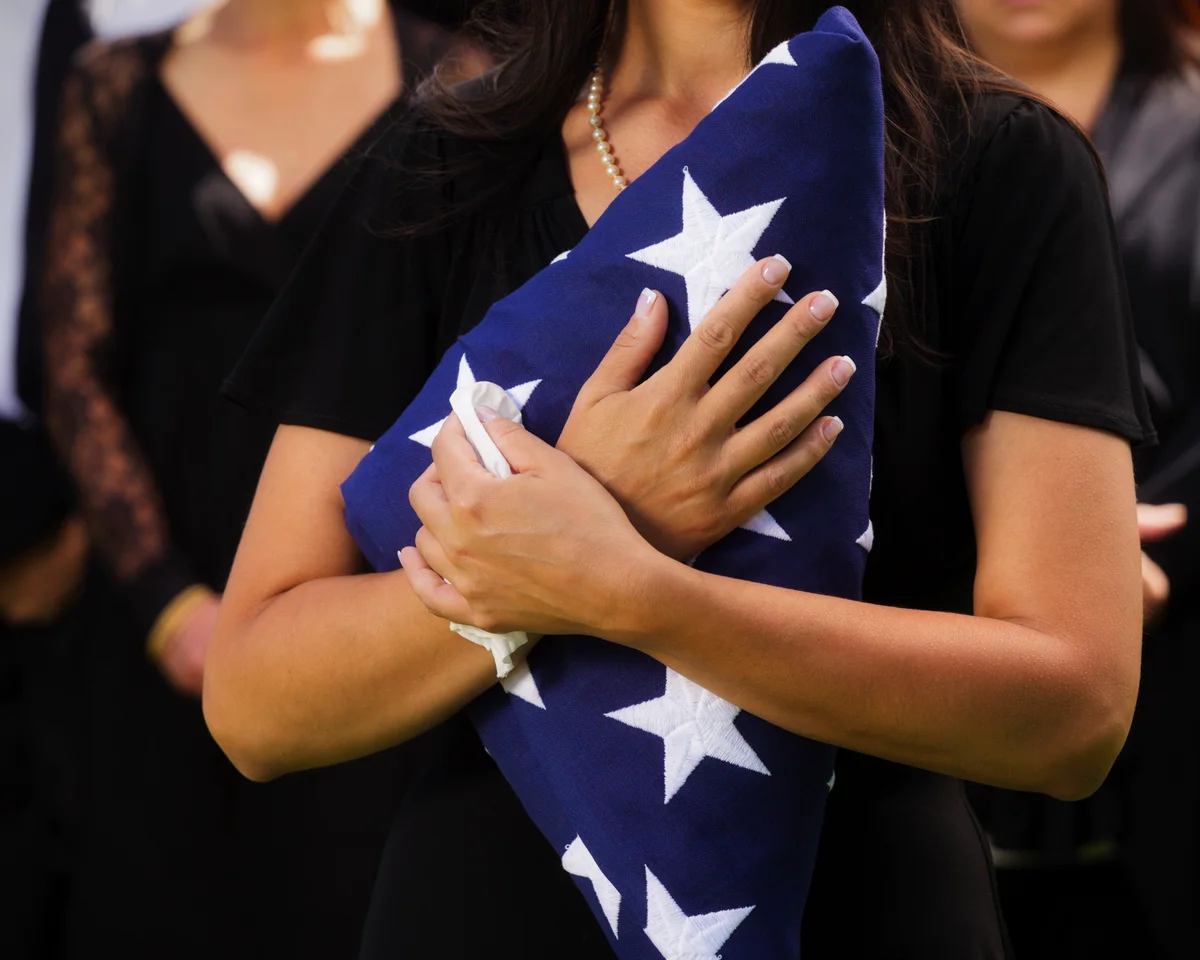 woman holding flag at military funeral
