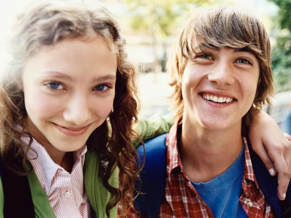 Teenage Girl Stands Smiling With Her Arm Around Her Friend