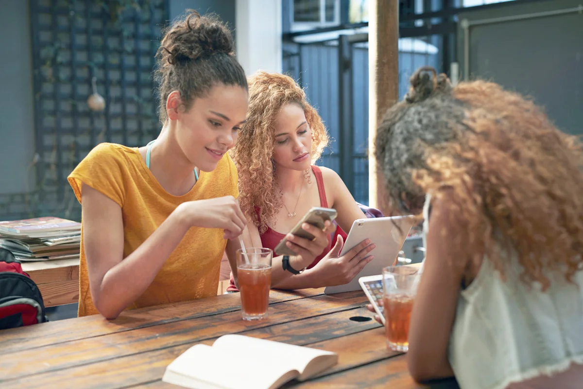 Young women looking at their own different phones and tablet