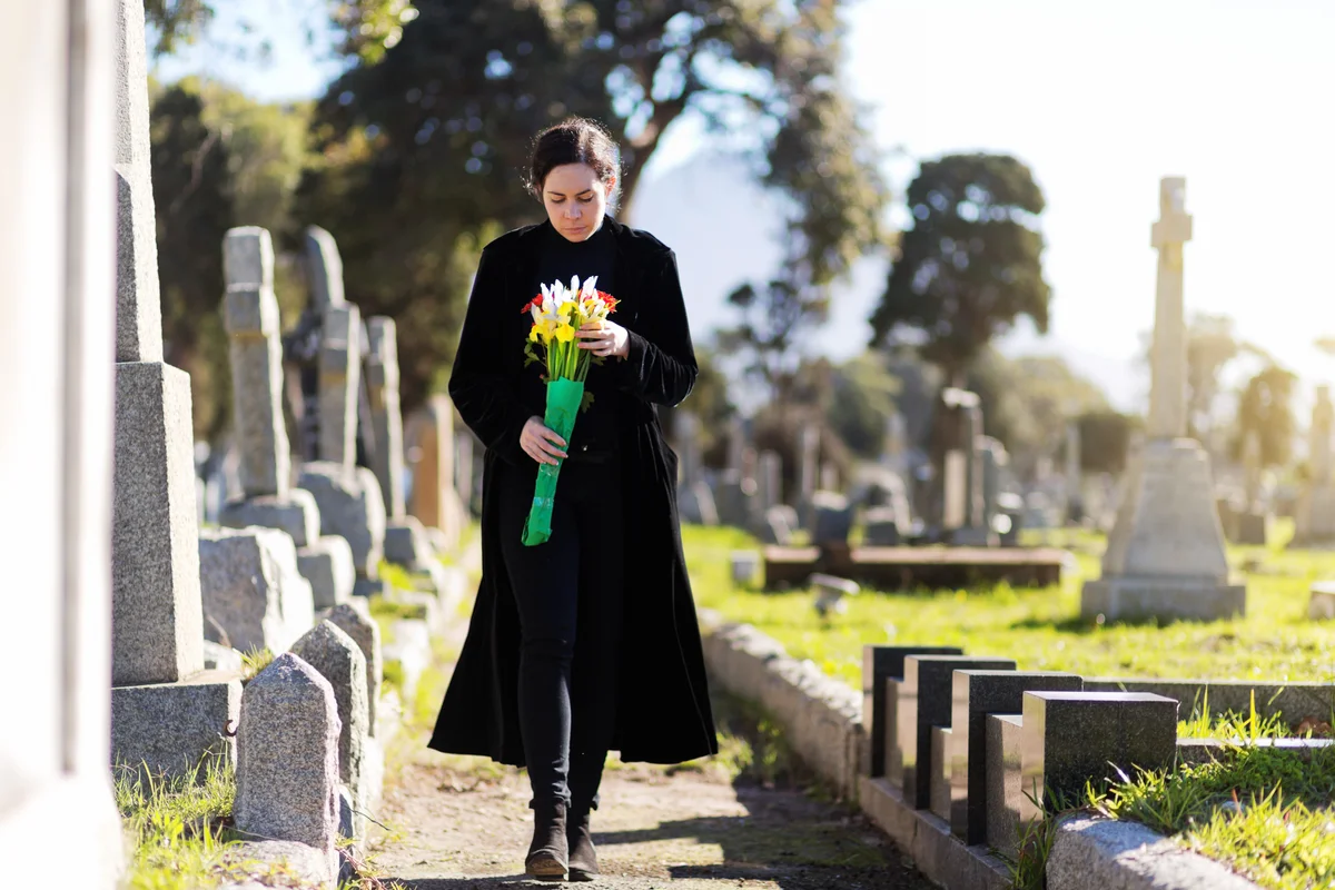 Woman in cemetery with flowers