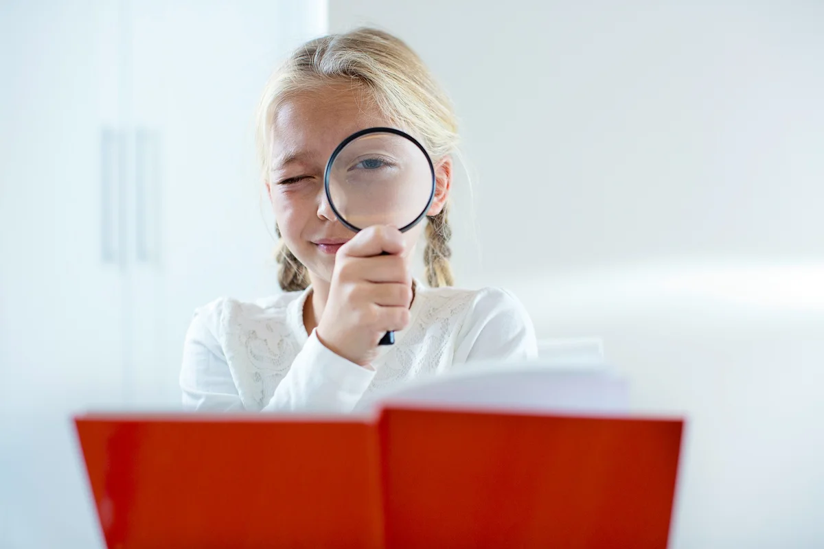 girl reading a clue and looking through a magnifying glass