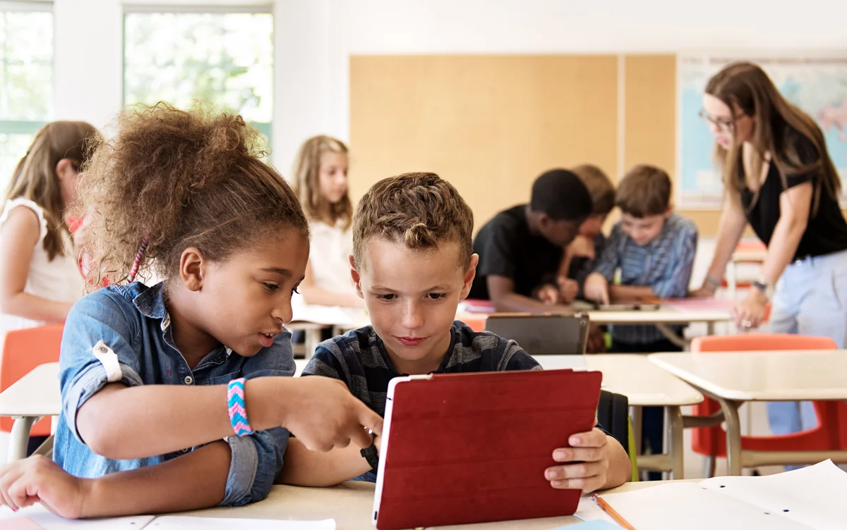 two kids looking on a device