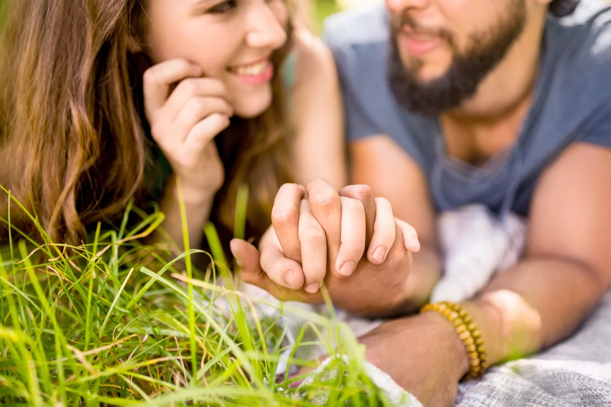 Affectionate couple holding hands while lying on the grass