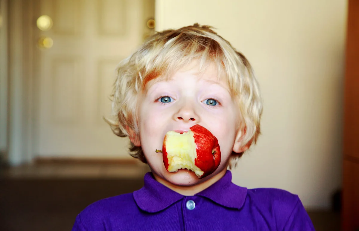 Young boy eating a red apple
