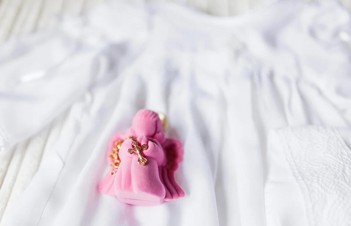 Golden cross for christening on pink gift box