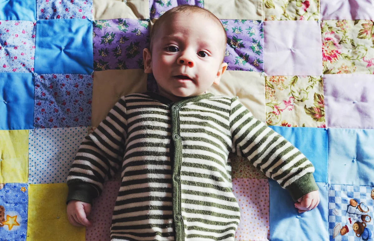 baby boy lies on a warm quilt in pajamas