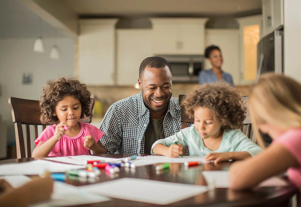 Father and children drawing in kitchen