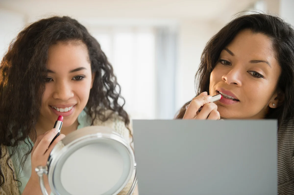 mother and daughter applying lipstick