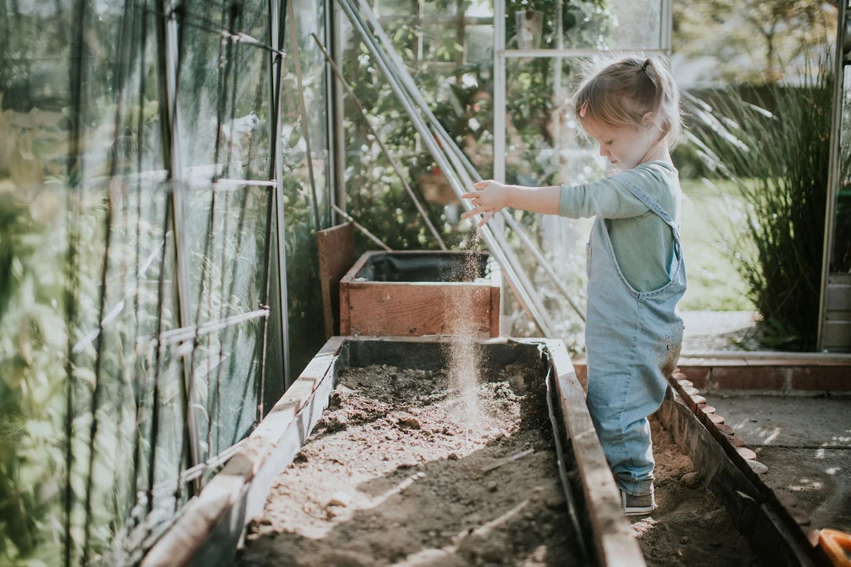 Girl digging in soil in greenhouse