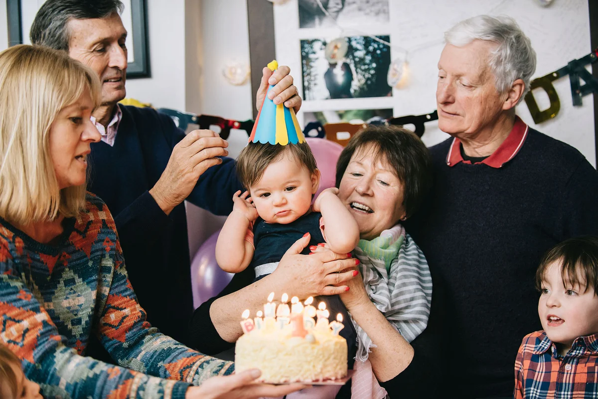 Family celebrating toddlers birthday with cake