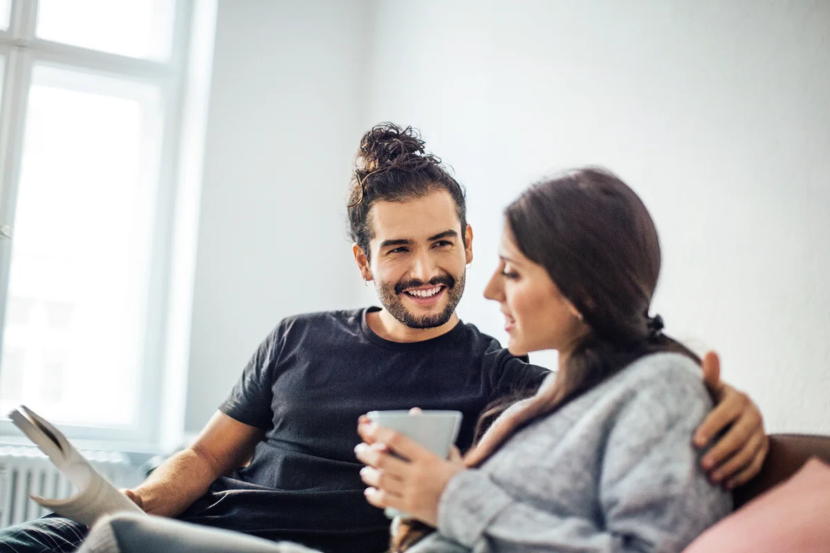 Man holding a book while looking at woman having coffee