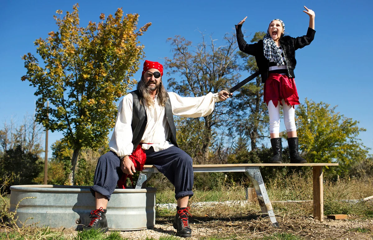 Father and daughter playing in pirate costumes outdoors