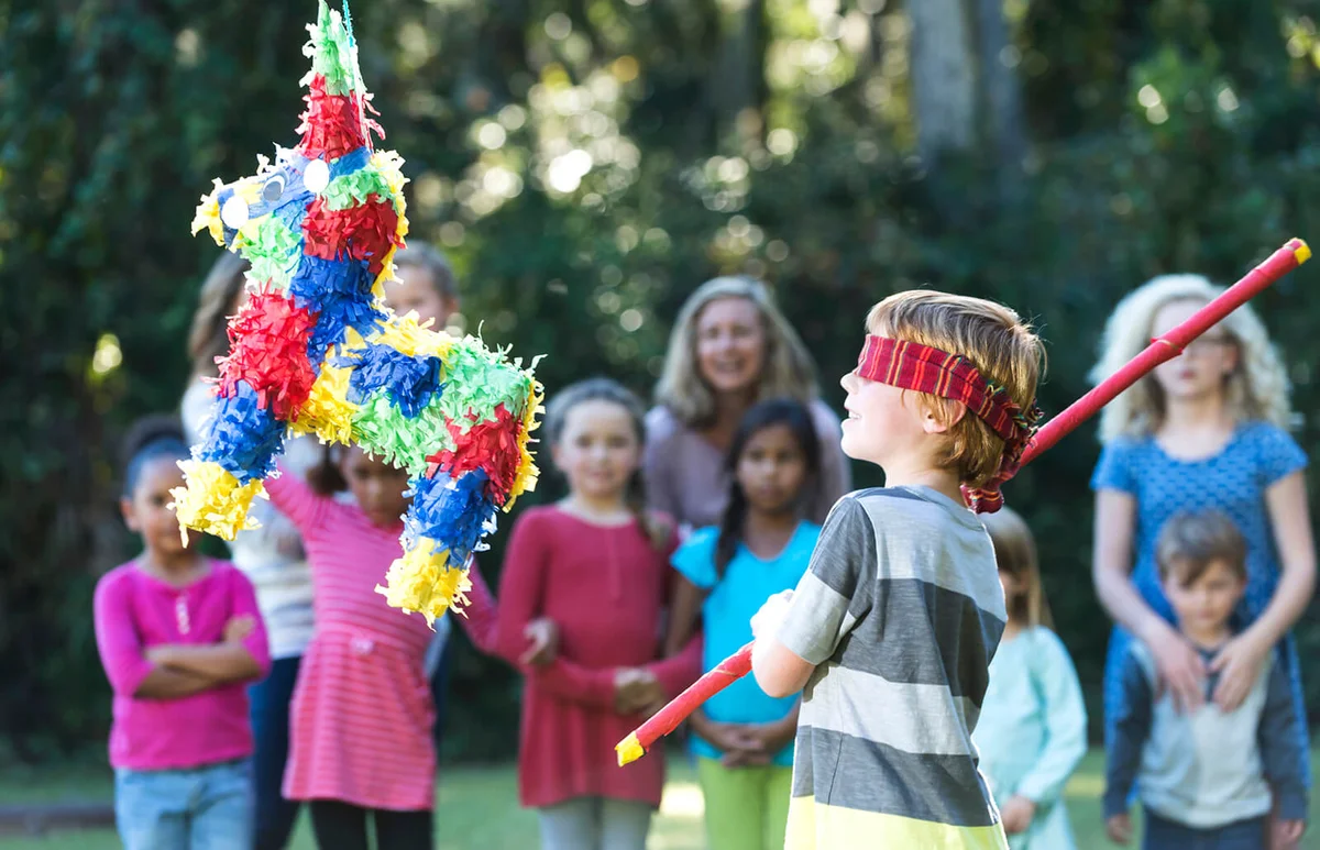 Boy at party hitting piñata with stick