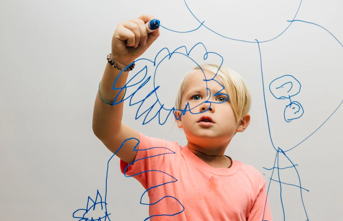 Boy drawing with marker pen onto glass wall