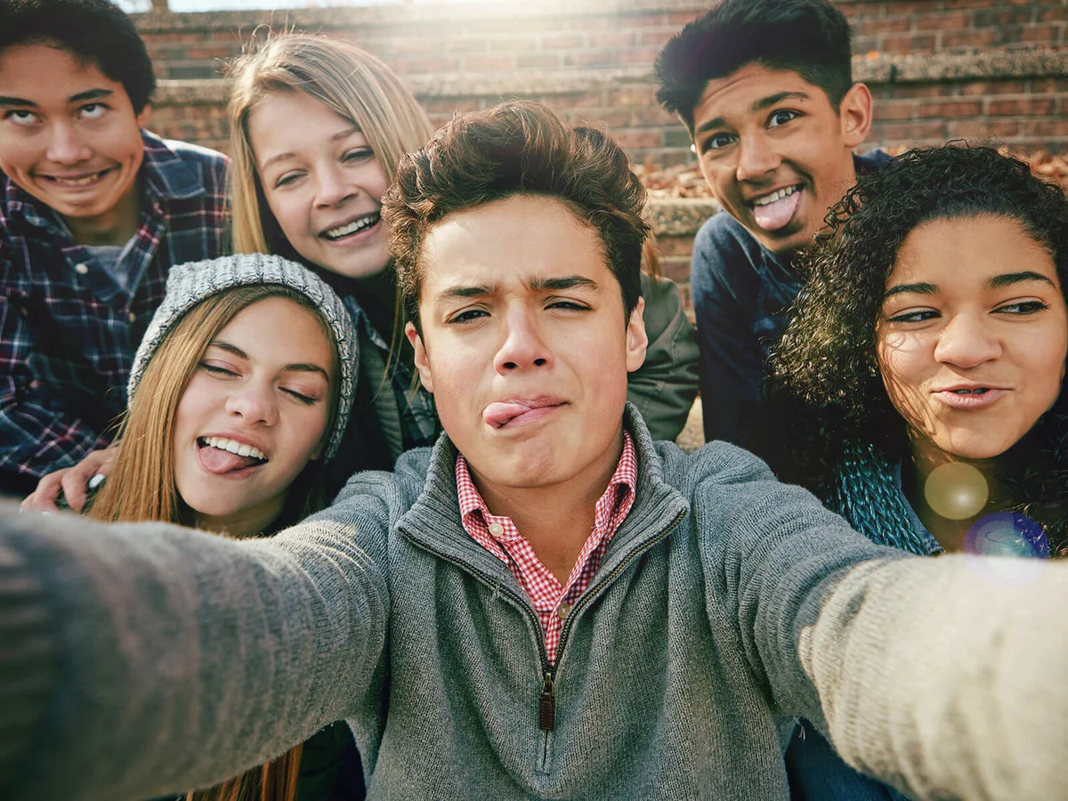 group of young friends posing for a selfie together outside
