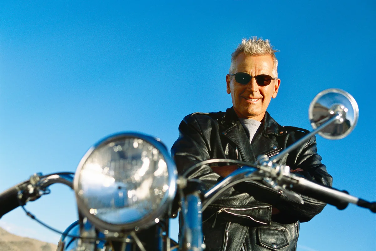 Portrait of a Mature Man Standing by a Stationary Motorbike