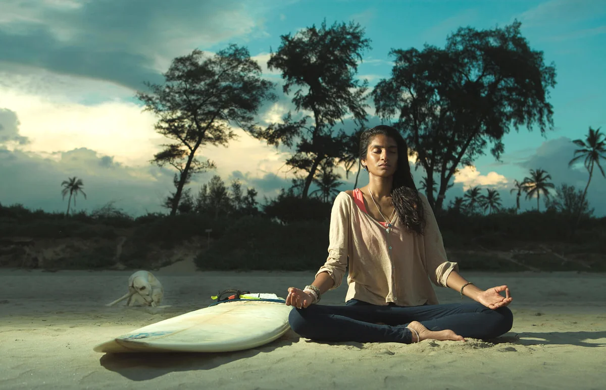 Woman With Dog Meditating While Sitting At Beach