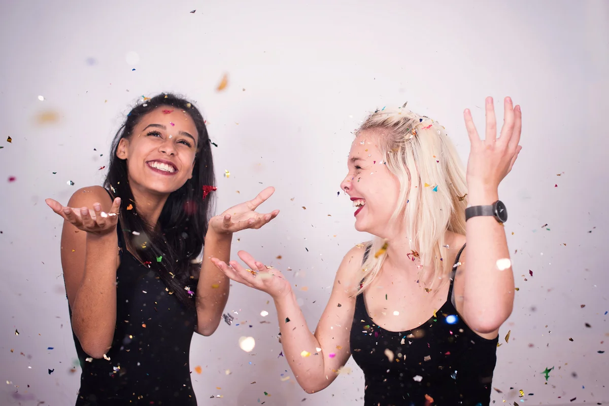 Two girls dancing with confetti flying
