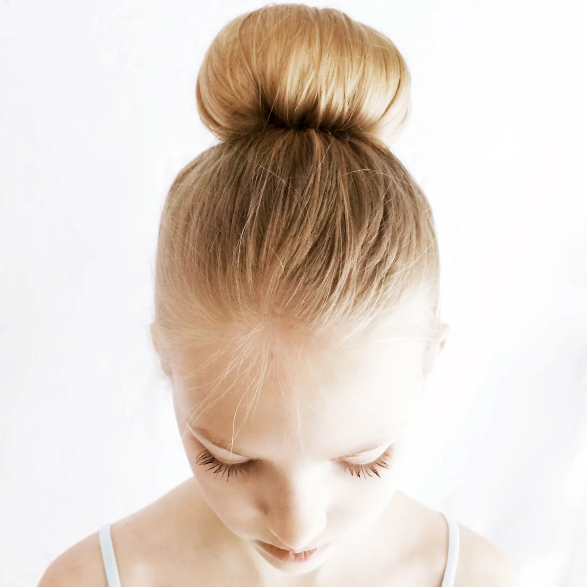 Portrait of a girl with a hair bun looking down